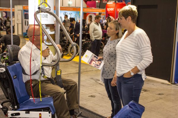 An exhibitor showcasing how a disability hoist works to expo visitors