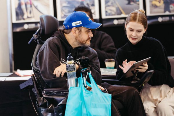 Exhibitor showing product samples to visitor in wheelchair