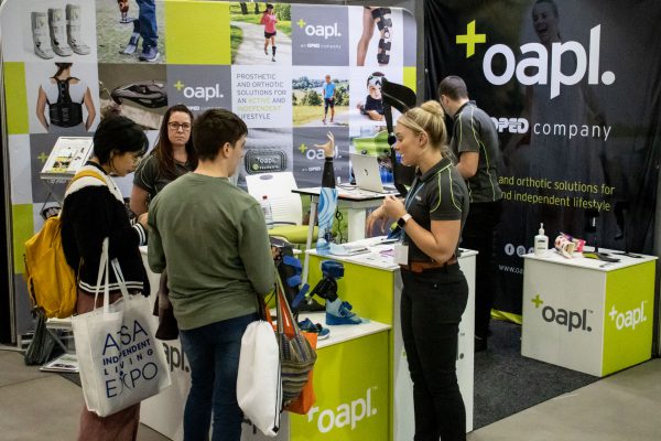 Oapl staff speaking with ATSA Expo visitors who are looking at a gallery of their products on display at their exhibition stand