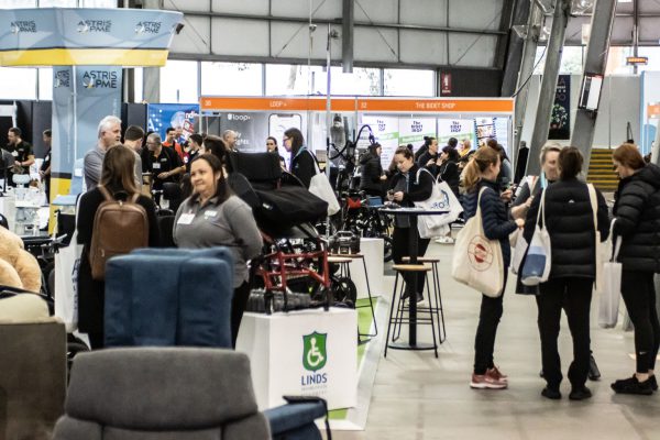 ATSA Melbourne visitors at the Linds exhibition stand with wheelchairs and seating products on display within their stand gallery