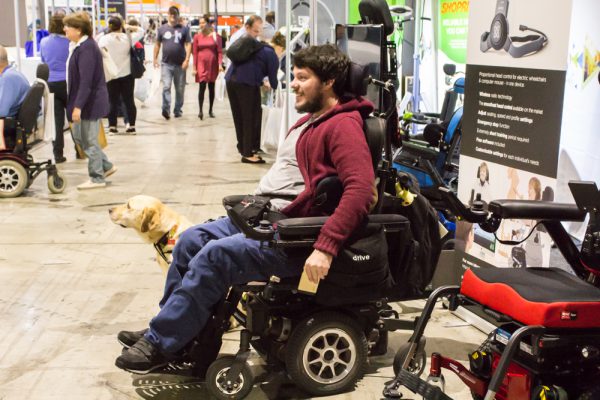 A man in a wheelchair with his guide dog looking at products on the ATSA Sydney Expo floor at 2019 event