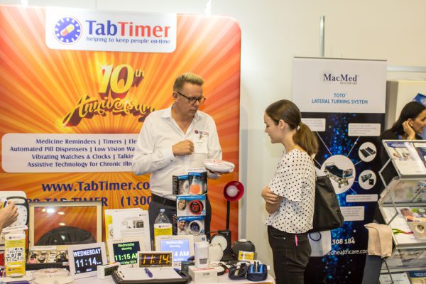 Tab Timer exhibition staff demonstrating one of their products to an ATSA Brisbane Expo visitor