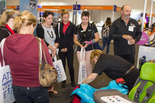 A group of visitors surrounding an exhibitor whilst getting a product demonstration of a child's car seat at the Brisbane Expo 2019