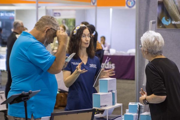 An exhibitor showcasing products to a visitor on the expo floor