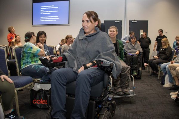 A wheelchair user showcasing an adaptive clothing jumper at fashion show gallery - ATSA Brisbane 2022