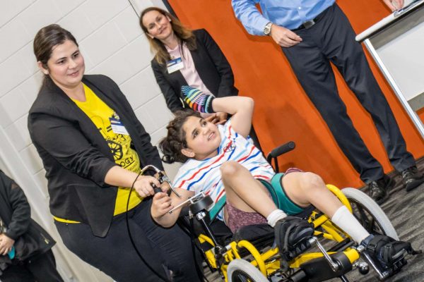 A young wheelchair user showcasing adaptive clothing items during ATSA Expo Fashion gallery