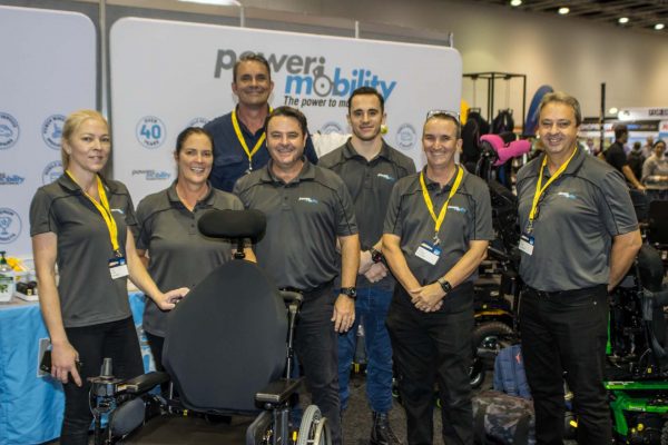 Power Mobility exhibition staff posing for a photo at their expo stand in Brisbane