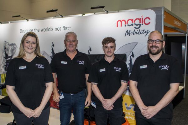 Magic Mobility exhibition staff posing for a photo at their expo stand in Brisbane