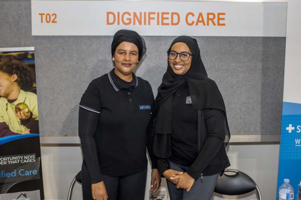 Two women from Dignified care at their exhibition stand smiling at the camera